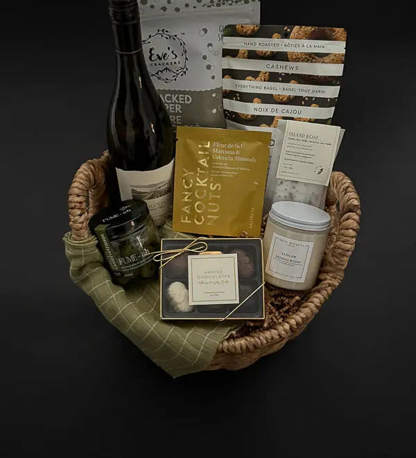 Side view of cozy gift basket featuring grounding candle, wine, and gourmet treats