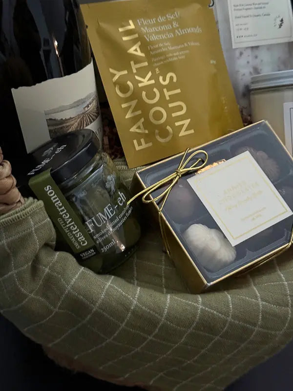 Flatlay of contents from Grounded gift basket including crackers, olives, chocolate, and wine