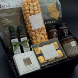 Curated artisan housewarming gift box featuring gourmet crackers, chocolates, infused olive oil, balsamic, and preserves.