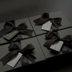 Black gift boxes with ribbons and labels on a dark background