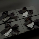 Black gift boxes with ribbons and labels on a dark background