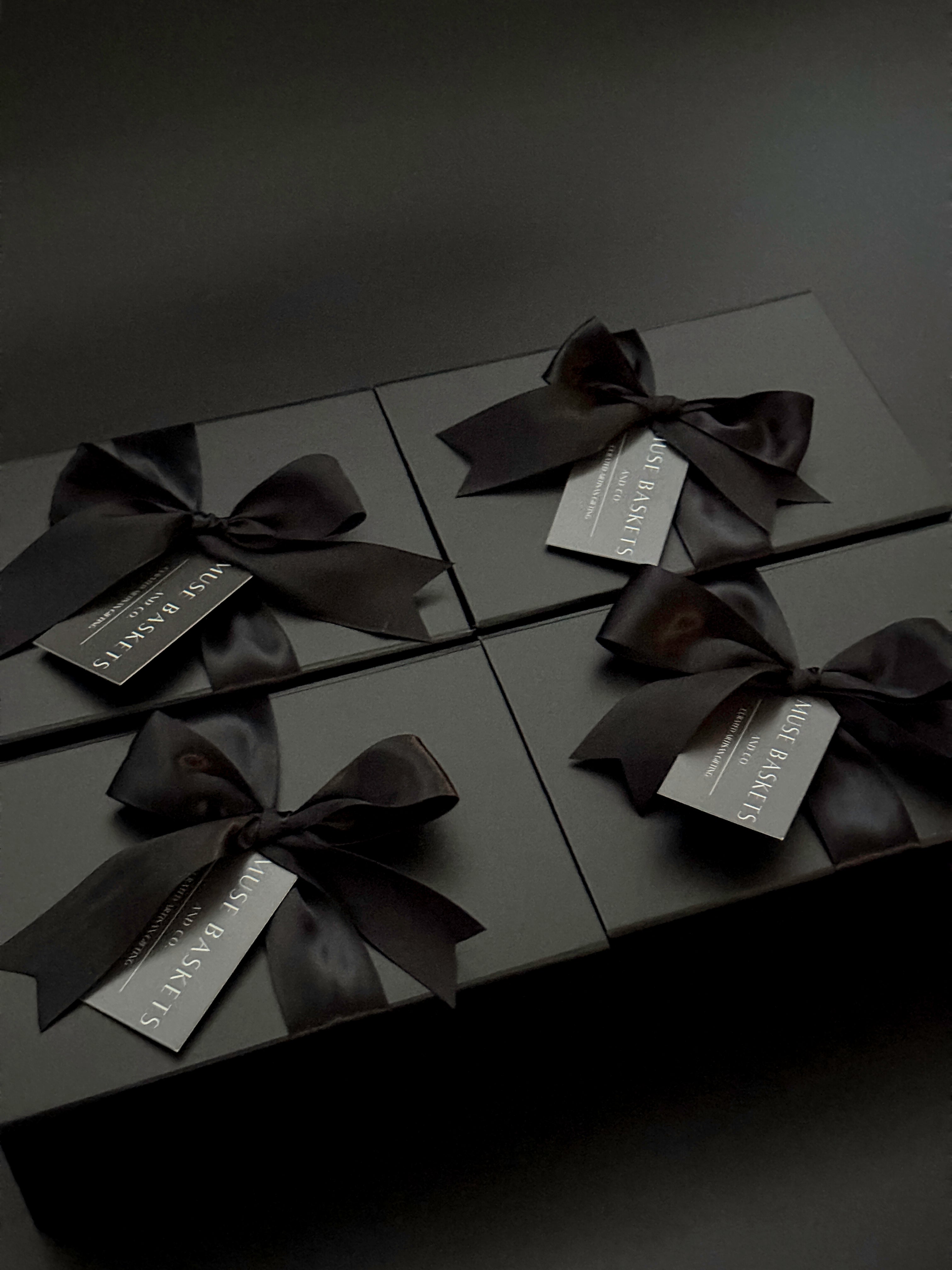 Black gift boxes with ribbons and labels on a dark background