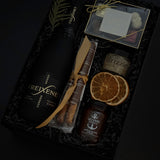 Obsidian Celebration Box with sparkling wine, chocolates, pretzels, honey, and fig spread arranged in a black gift box with festive greenery and ribbon.