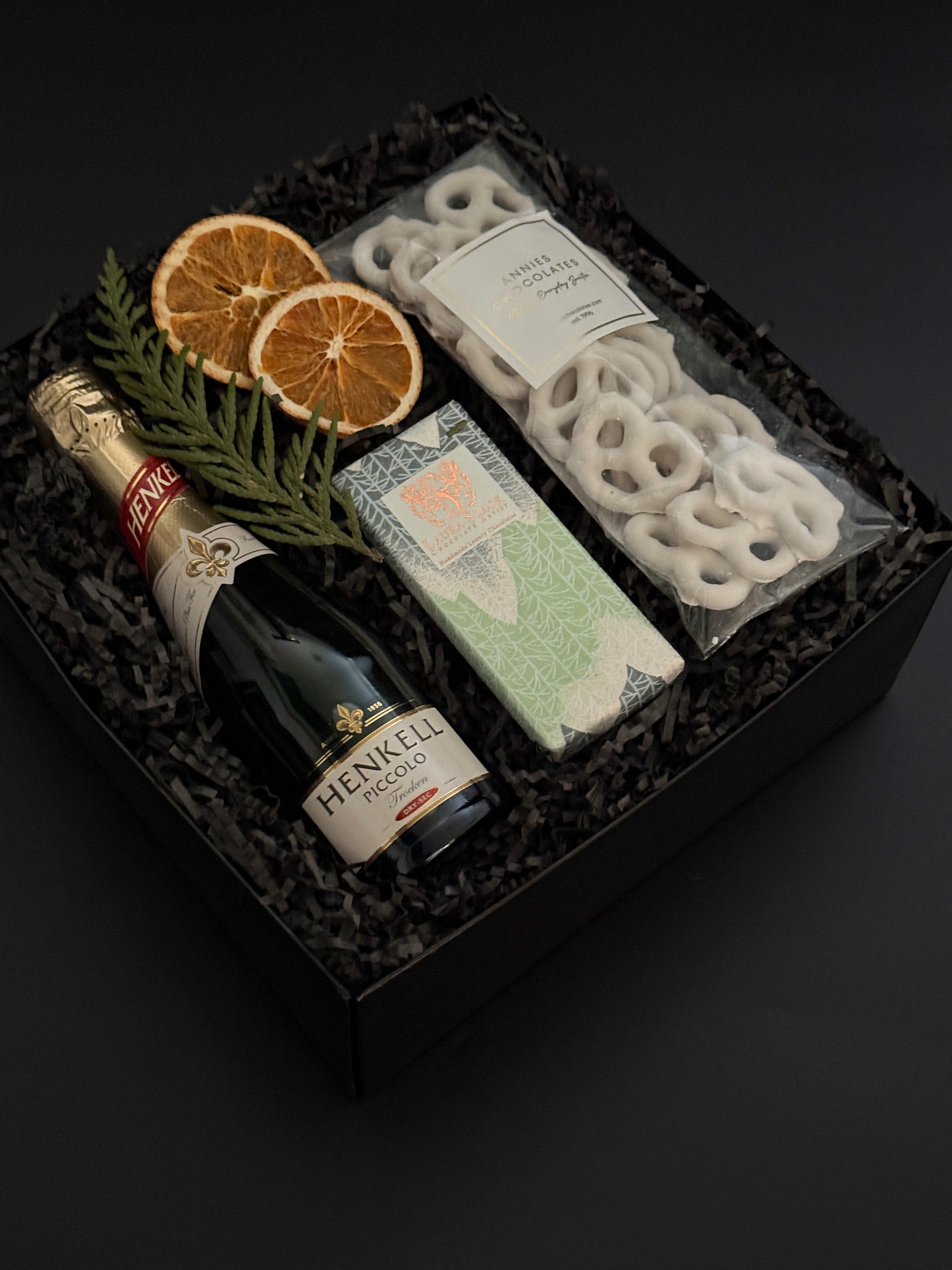 Étoile holiday gift box with sparkling wine, artisan chocolate, pretzels, and festive citrus accents.