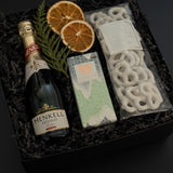 Corporate holiday gift box featuring Henkell sparkling wine, chocolate bar, and white chocolate pretzels.