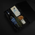 Close-up of artisan chocolate bar and gold tin candle from the Élan Bleu Gift Box, showcasing refined craftsmanship and understated luxury.