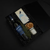 Close-up of artisan chocolate bar and gold tin candle from the Élan Bleu Gift Box, showcasing refined craftsmanship and understated luxury.