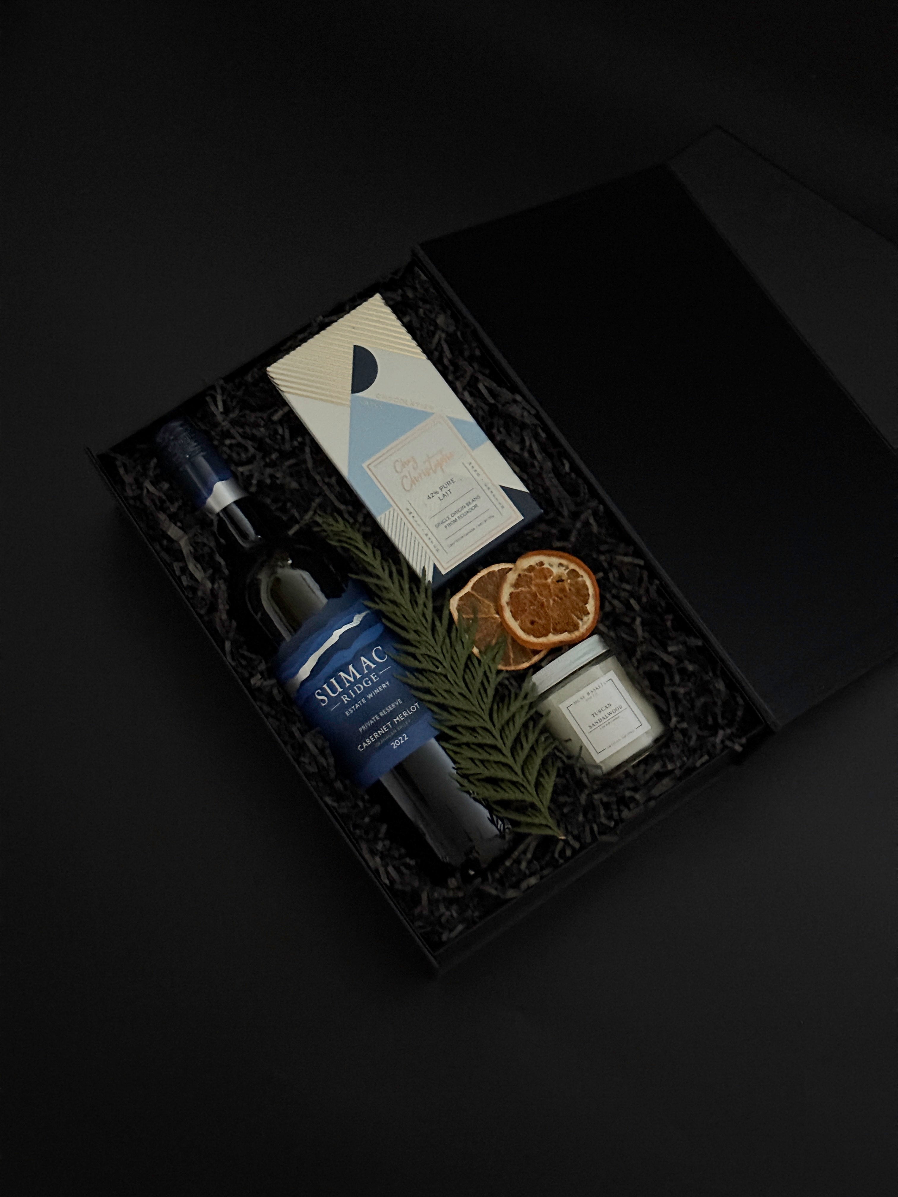 Close-up of artisan chocolate bar and gold tin candle from the Élan Bleu Gift Box, showcasing refined craftsmanship and understated luxury.