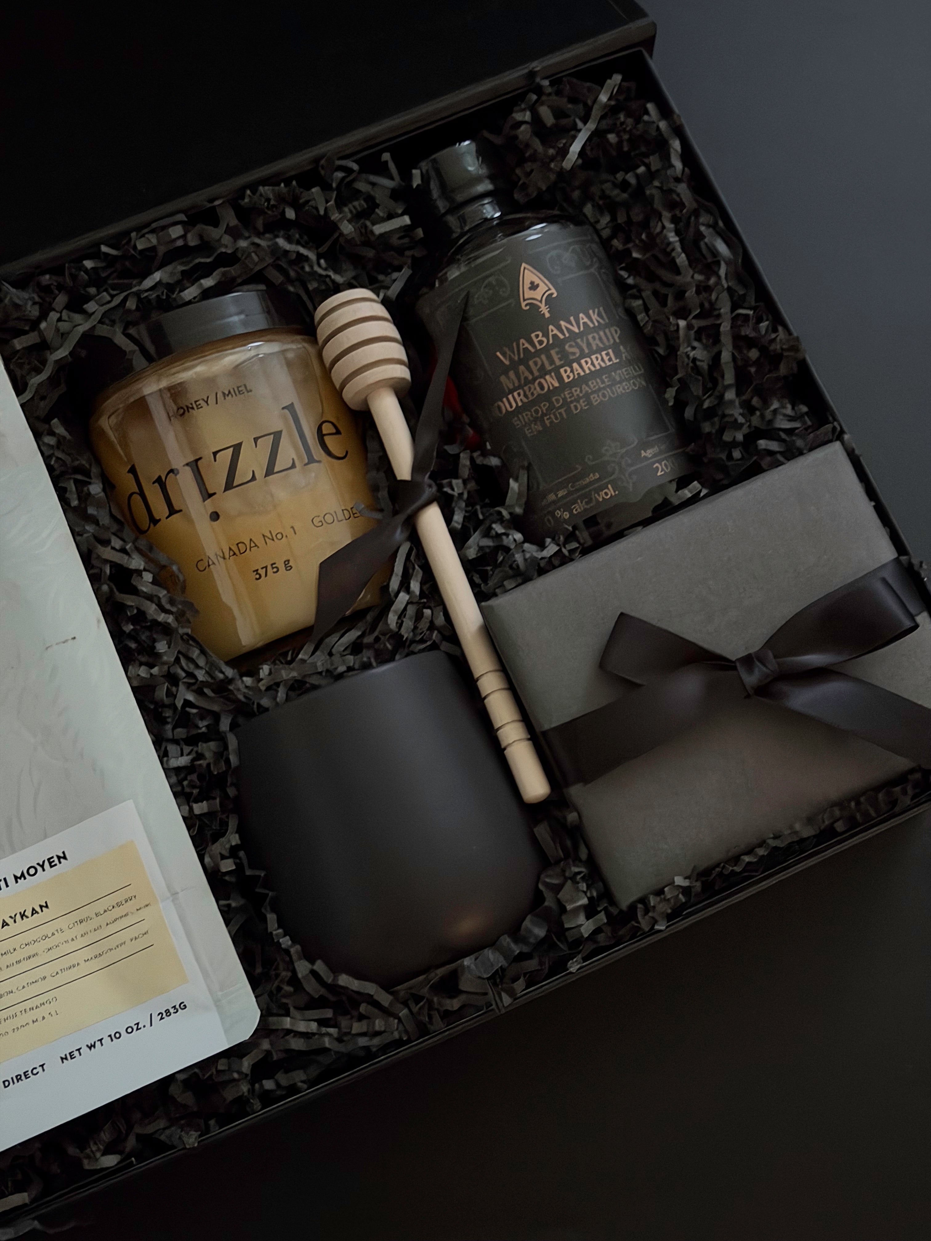 Close-up of Solenne’s curated contents — golden honey, stoneware mug, gourmet coffee, and maple syrup styled elegantly.