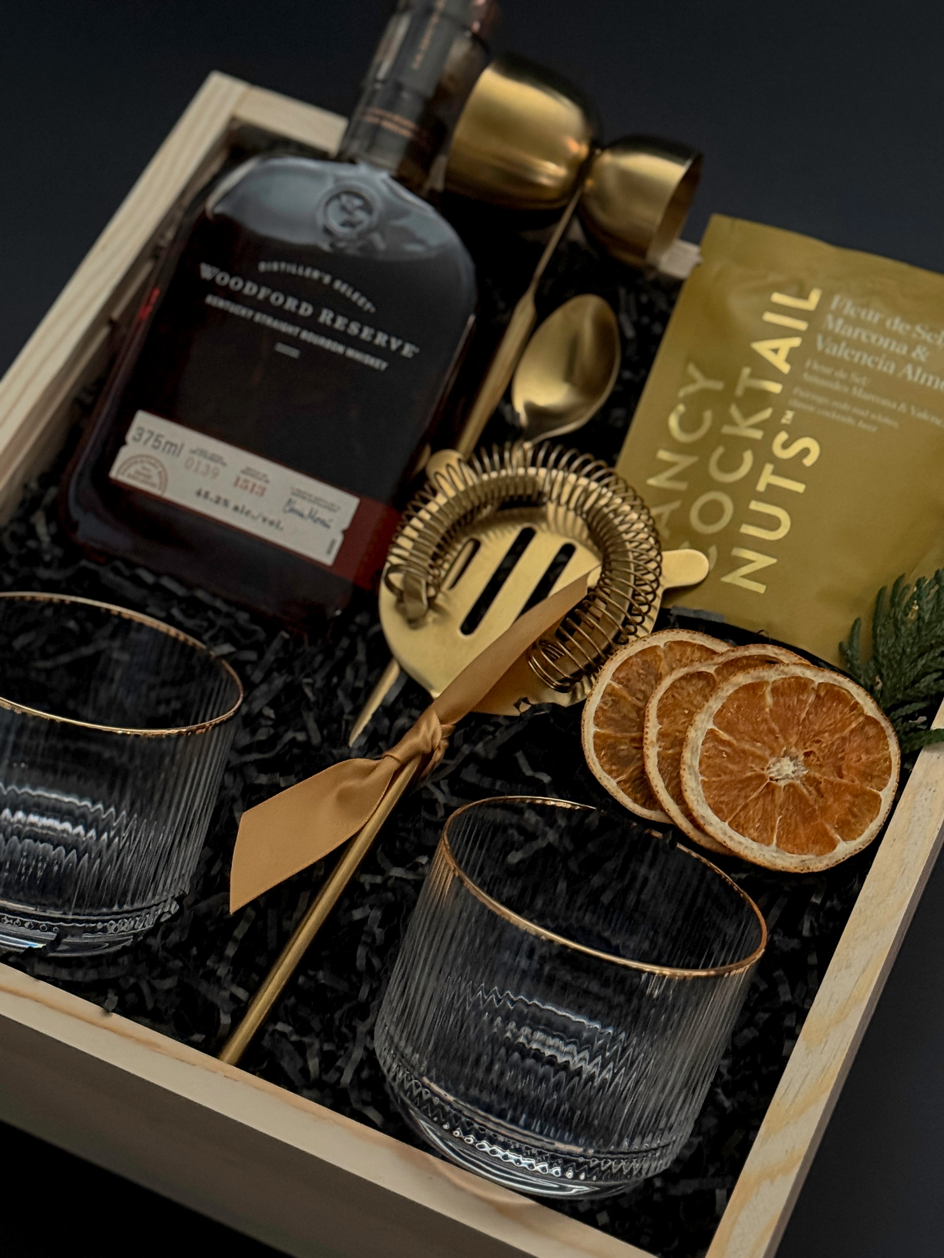 Holiday whiskey gift box with Woodford Reserve, gold tools, almonds, and mandarins