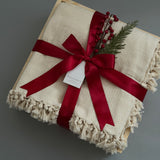 Closed gift box with cream blanket and holiday decorations, perfect for  corporate clients and colleagues.