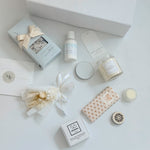 Collection of beauty products including candles, soaps, and skincare items on a white surface.
