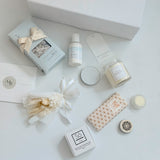 Collection of beauty products including candles, soaps, and skincare items on a white surface.