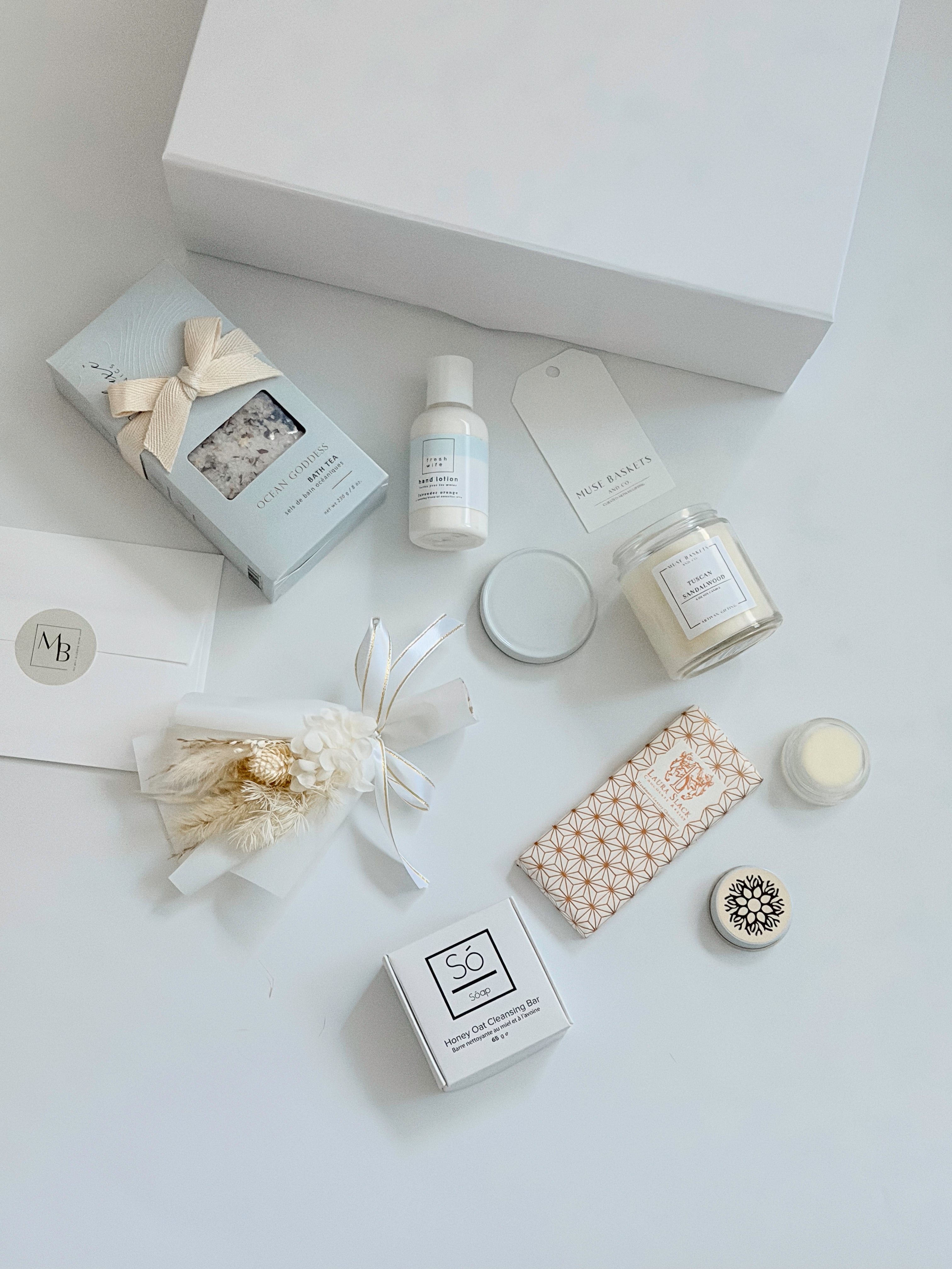 Collection of beauty products including candles, soaps, and skincare items on a white surface.