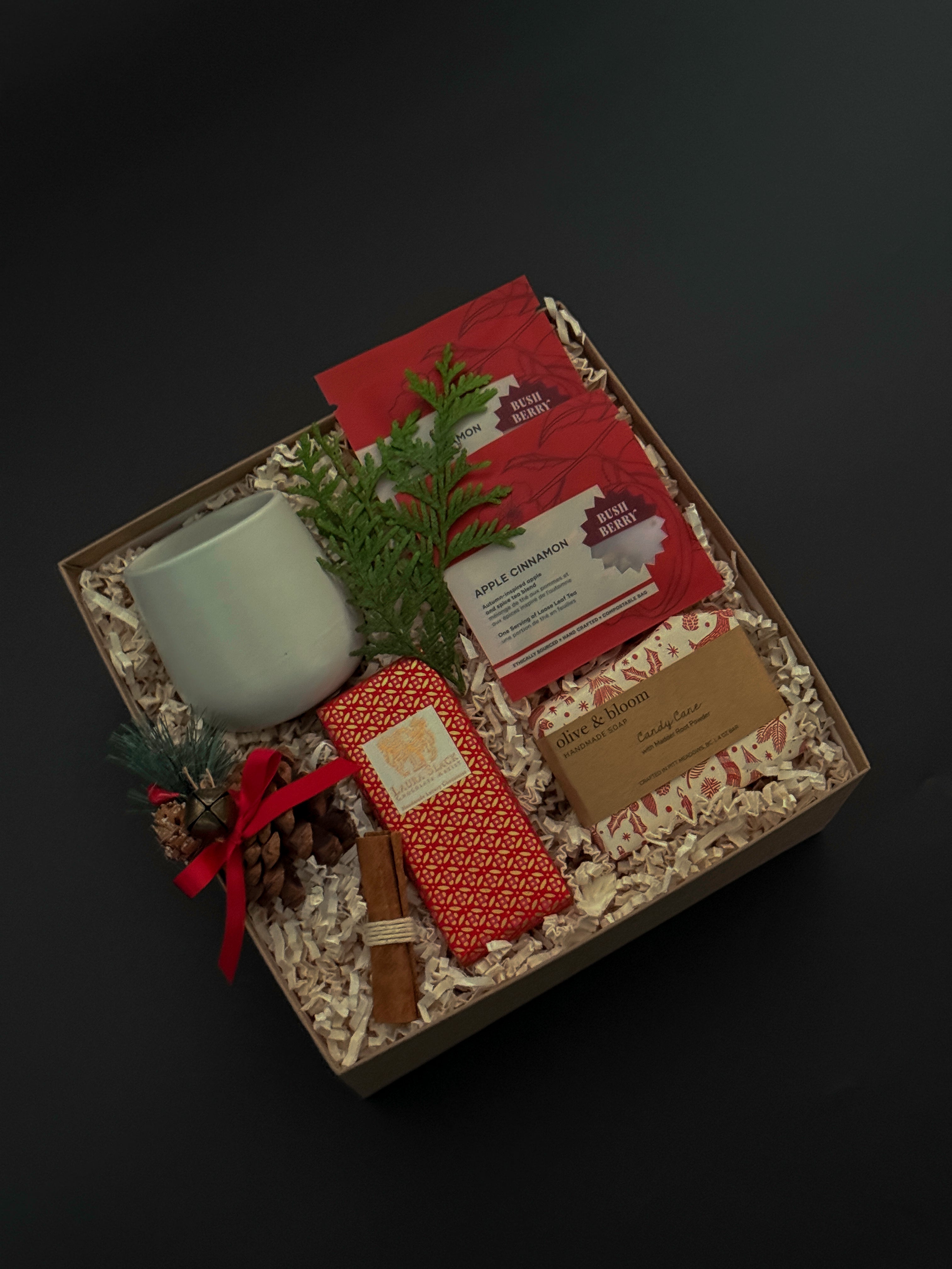 Executive holiday gift box with artisan chocolate, soap, cup, and festive ribbon.