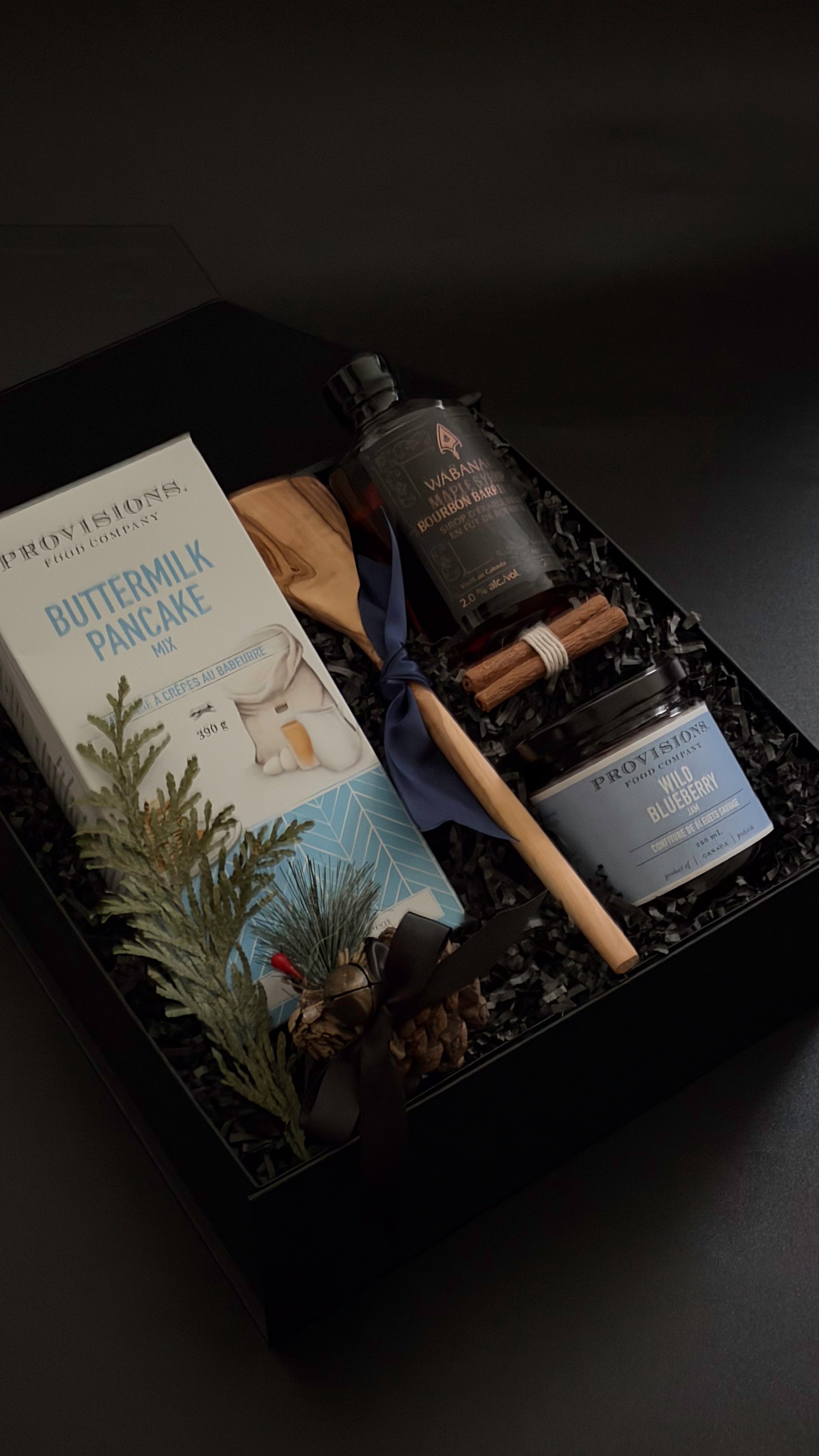 Cozy winter breakfast gift basket with Canadian gourmet products and olive wood utensil.