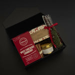 Gift set with white chocolate cranberry cookies, a candle, and other items in a black box on a dark background.