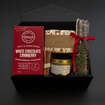 Holiday gift box with artisan soap, candle, cookies, and chocolate pretzels.