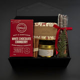 Holiday gift box with artisan soap, candle, cookies, and chocolate pretzels.