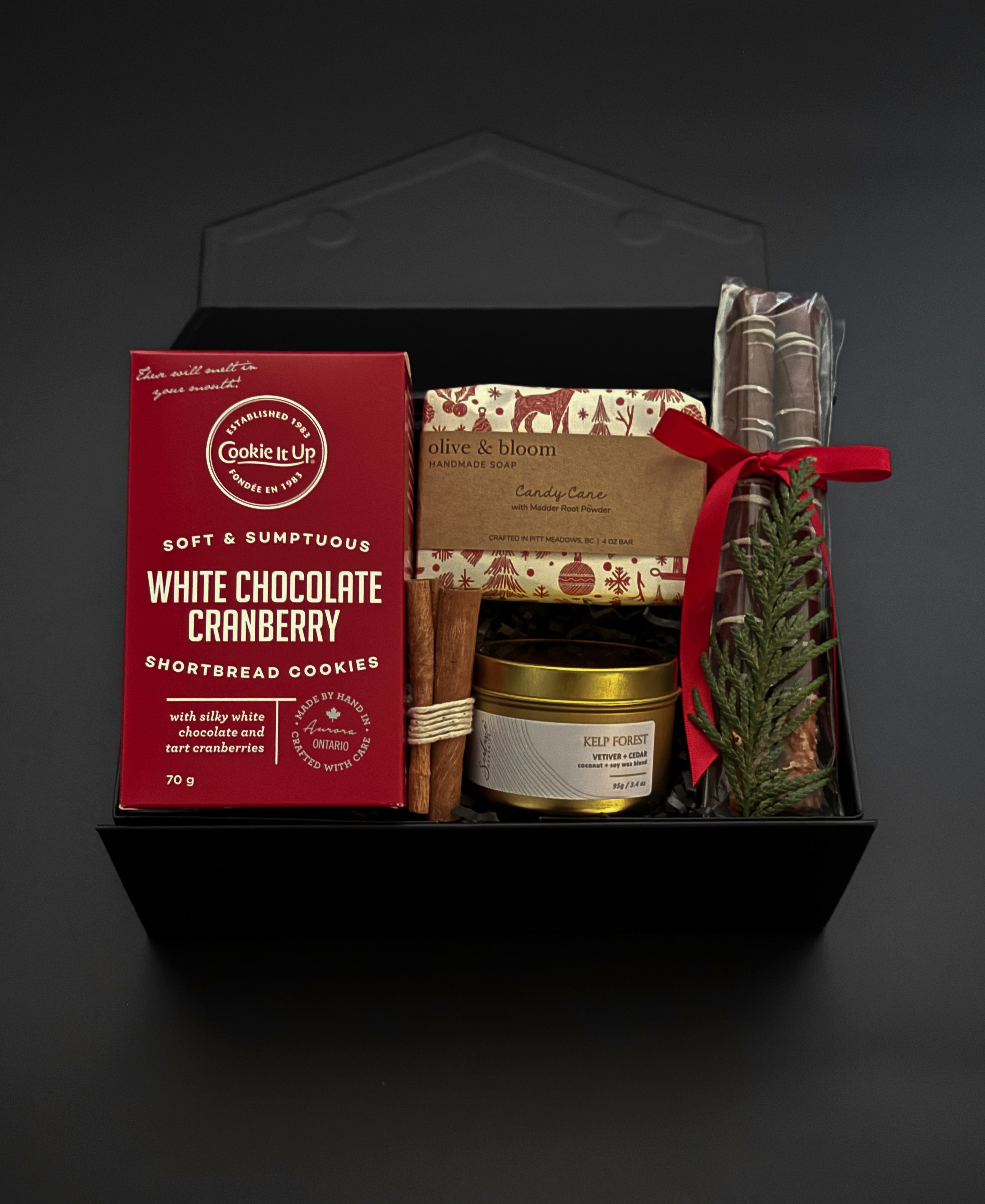 Holiday gift box with artisan soap, candle, cookies, and chocolate pretzels.