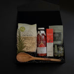 Flat lay of La Tavola Italiana Gift Box — black box filled with artisanal pasta, passata, and gourmet accompaniments, styled elegantly on a marble surface.