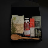 Flat lay of La Tavola Italiana Gift Box — black box filled with artisanal pasta, passata, and gourmet accompaniments, styled elegantly on a marble surface.