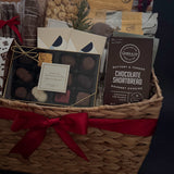 Gift basket with assorted items including a box of chocolates and a bag of cookies on a dark background.