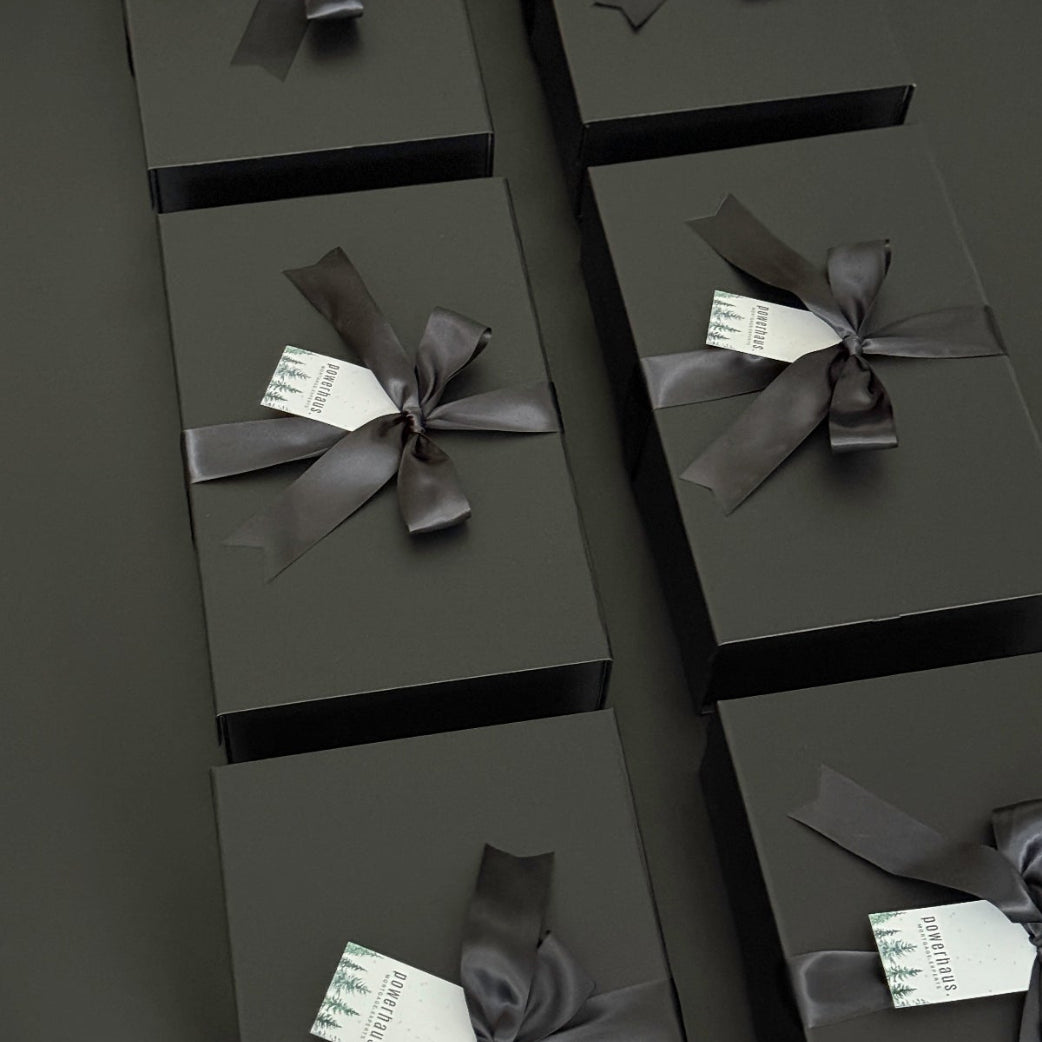 Elegant black gift boxes with satin ribbon and branded Muse Baskets tags, arranged for luxury corporate or holiday gifting