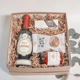 Rustic Charcuterie Gift Box with Italian red wine, brie, cashews, and red pepper jelly in a luxe kraft box with ribbon.