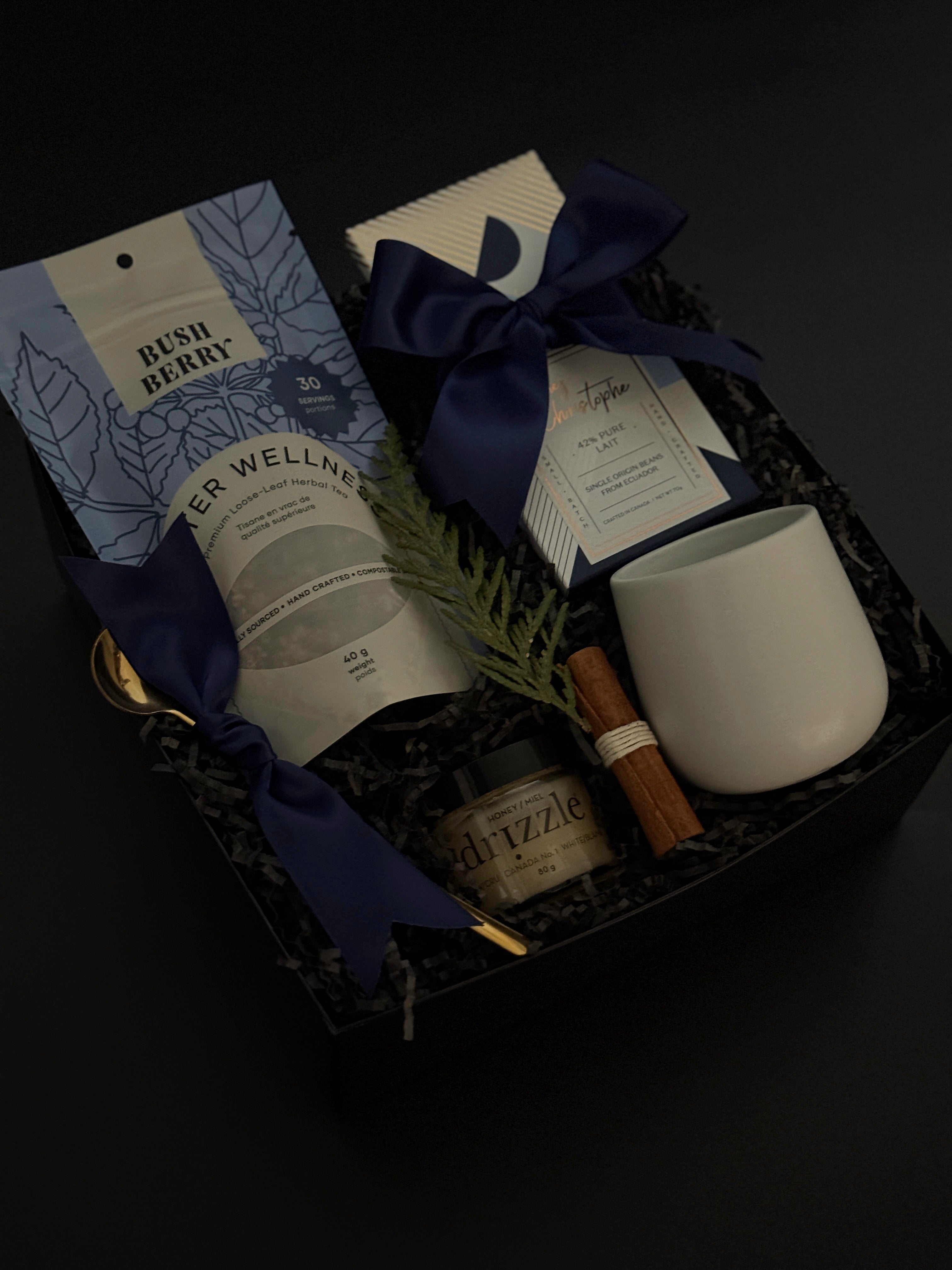 Sanctuary in Winter gift box featuring winter wellness tea, milk chocolate bar, honey, stoneware mug, and seasonal accents in a black bo