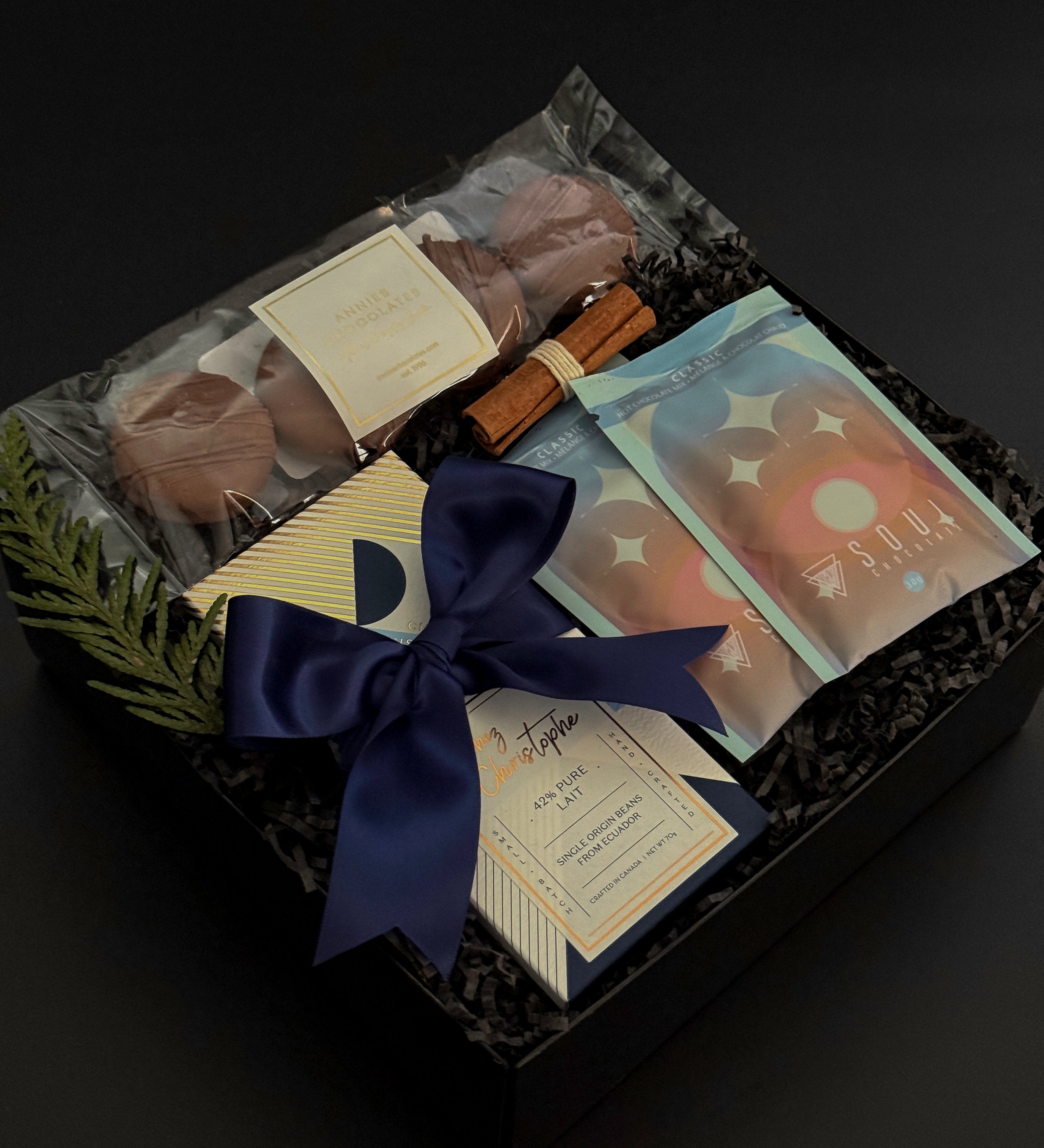 Flat lay of The Chocolate Indulgence gift box with cocoa, chocolate bar, cookies, and festive cinnamon bundle.