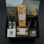 Gourmet gift basket with various snacks and drinks on a dark background