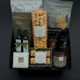 Gourmet gift basket with various snacks and drinks on a dark background