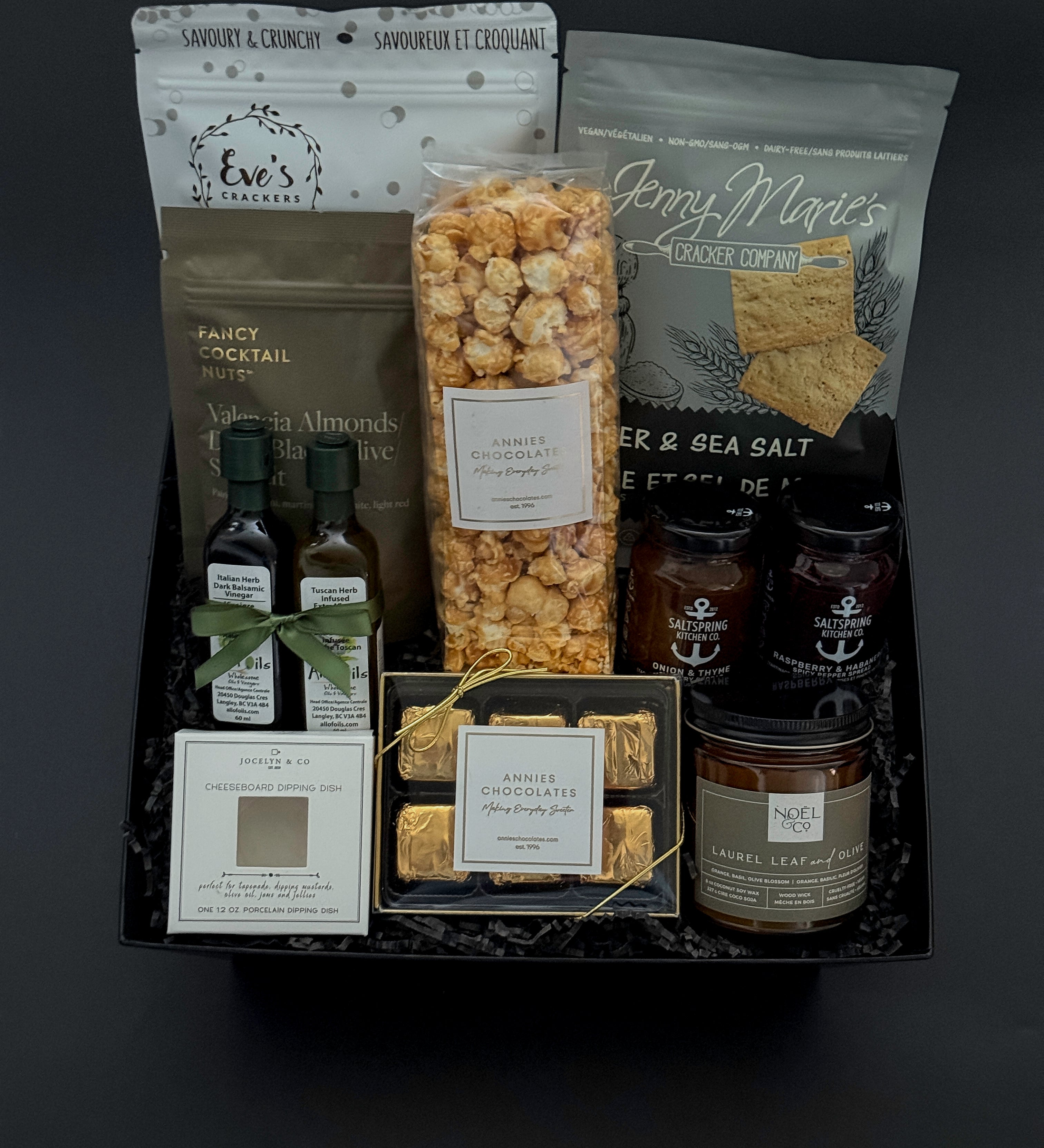Gourmet gift basket with various snacks and drinks on a dark background