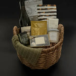 Grounded luxury gift basket with wine, candle, truffles, and savoury snacks in wicker basket