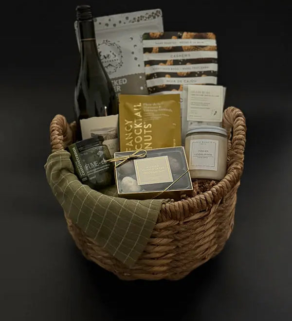 Grounded luxury gift basket with wine, candle, truffles, and savoury snacks in wicker basket