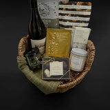 Side view of cozy gift basket featuring grounding candle, wine, and gourmet treats