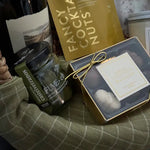 Flatlay of contents from Grounded gift basket including crackers, olives, chocolate, and wine