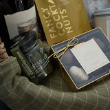 Flatlay of contents from Grounded gift basket including crackers, olives, chocolate, and wine