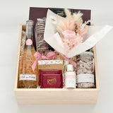 Gift basket with champagne, flowers, and other items on a white background