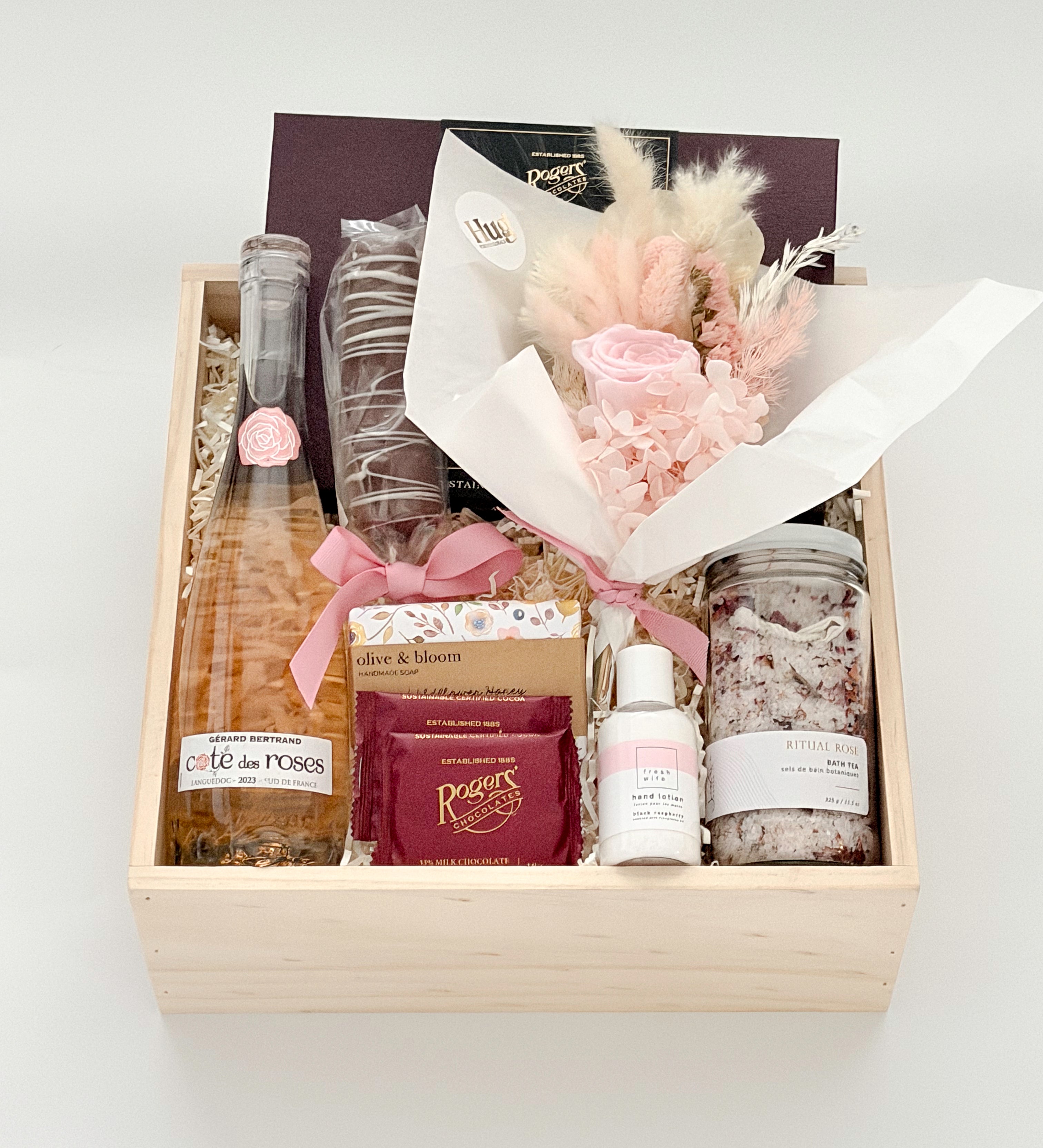 Gift basket with champagne, flowers, and other items on a white background
