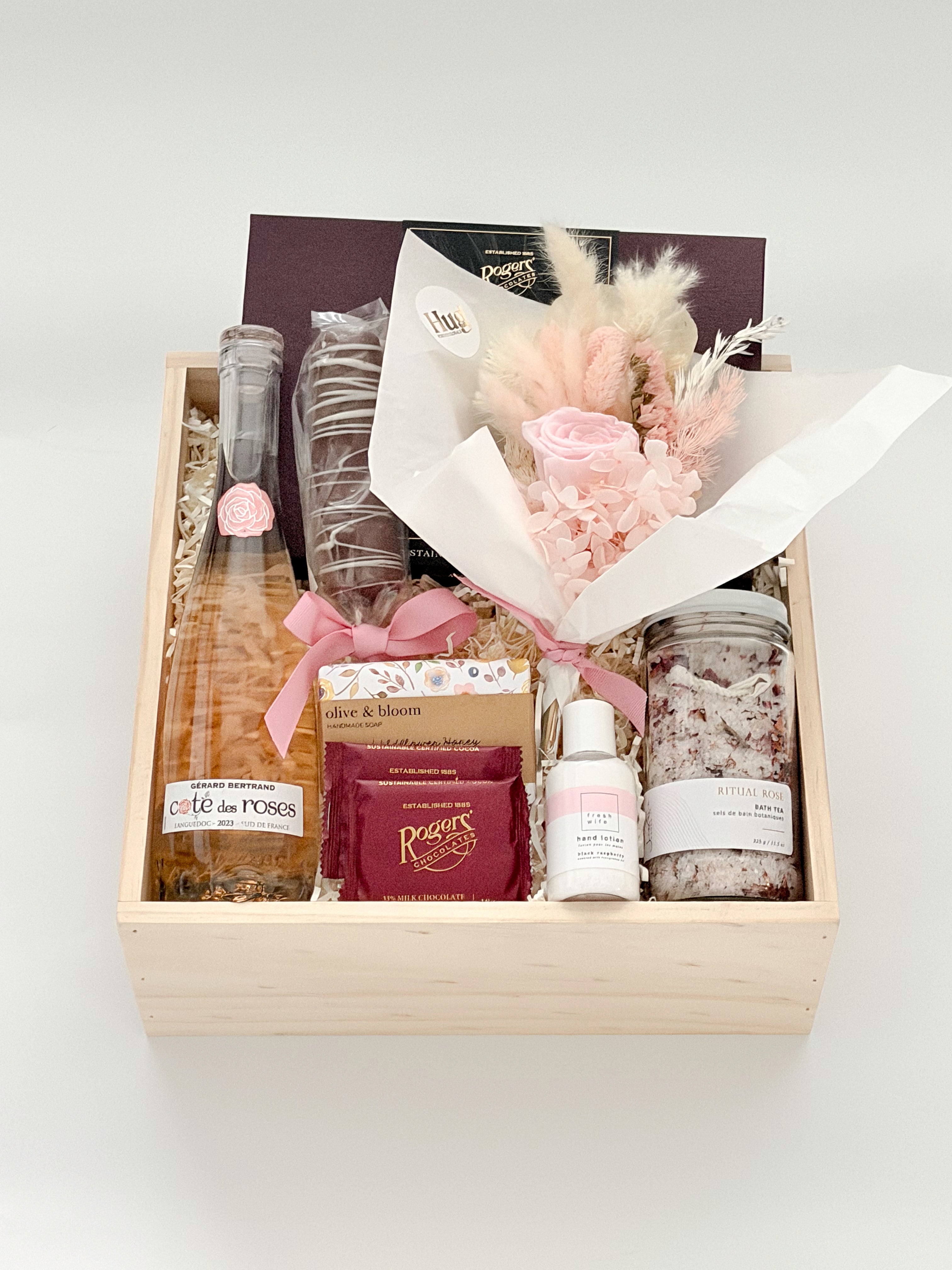 Gift basket with champagne, flowers, and other items on a white background