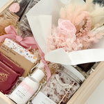 Gift set with skincare products and a bouquet of flowers in a box.