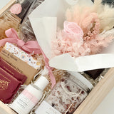 Gift set with skincare products and a bouquet of flowers in a box.