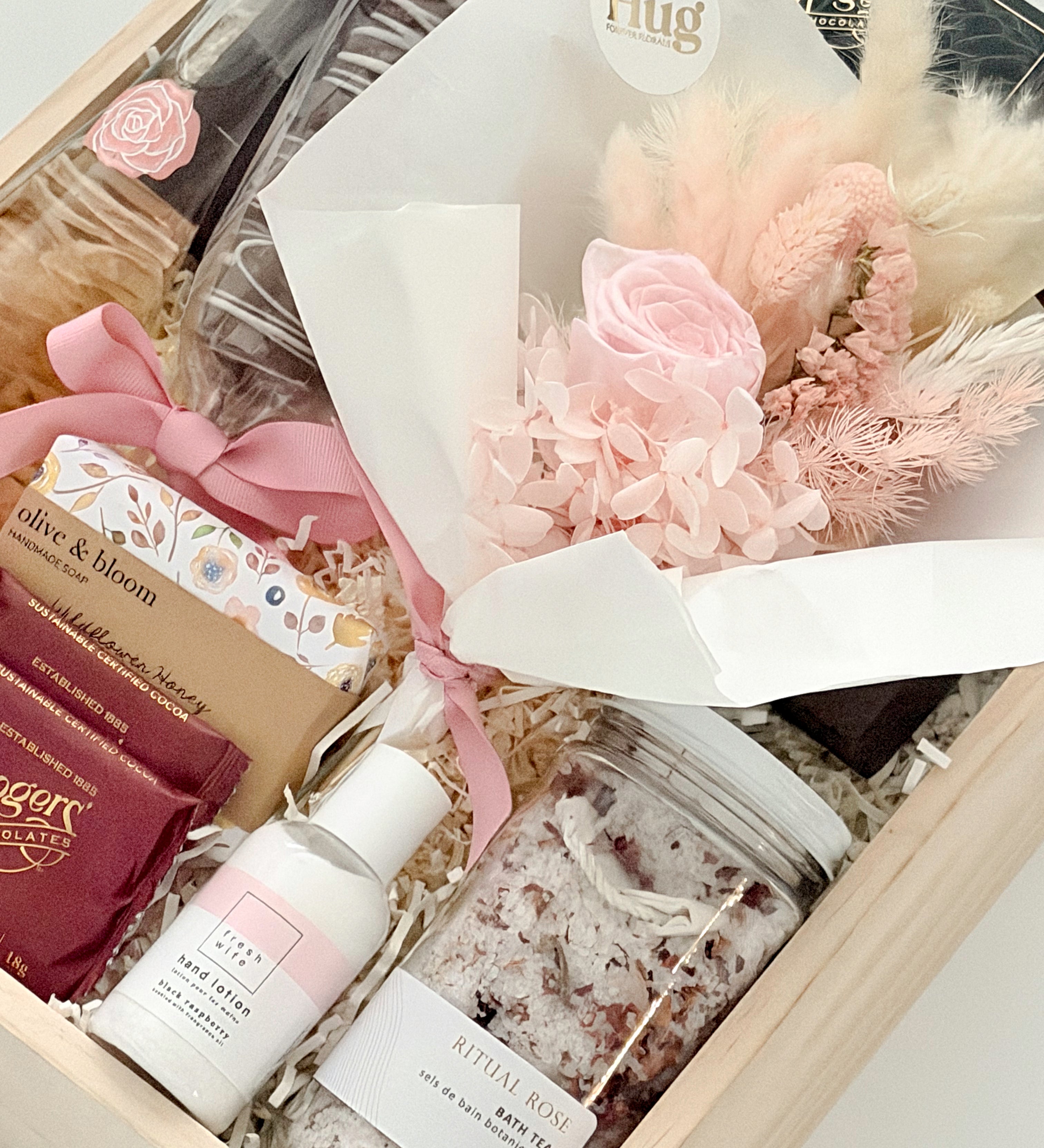 Gift set with skincare products and a bouquet of flowers in a box.