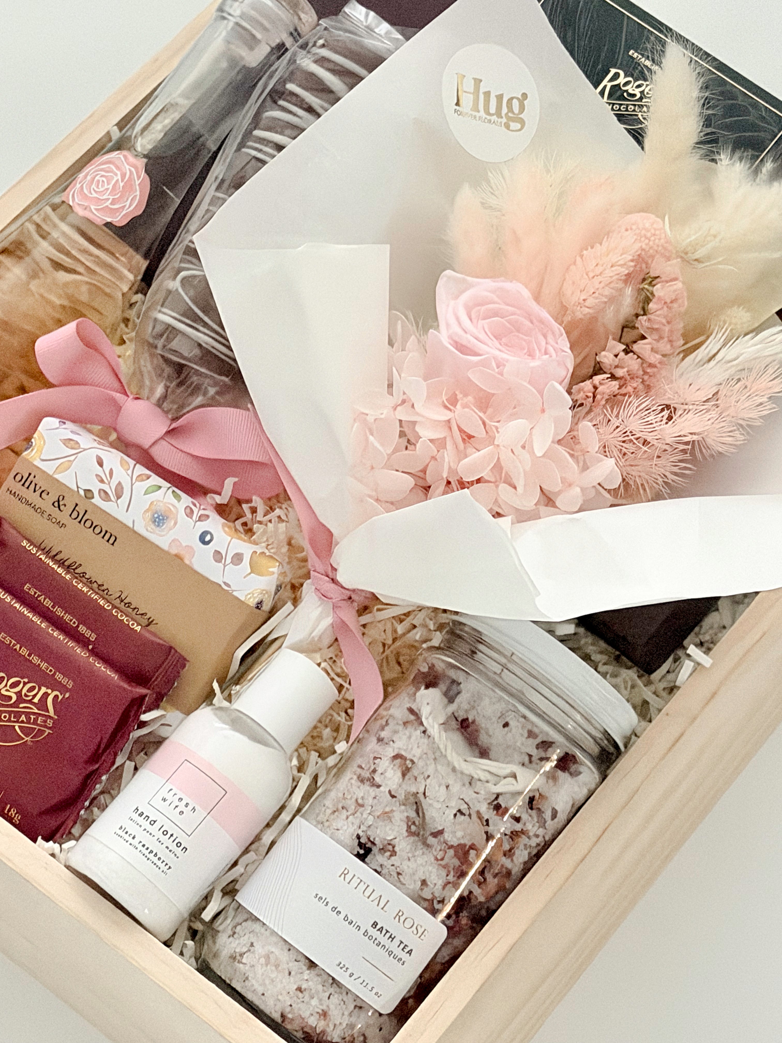 Gift set with skincare products and a bouquet of flowers in a box.