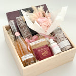 Gift basket with bottles, flowers, and other items on a white background