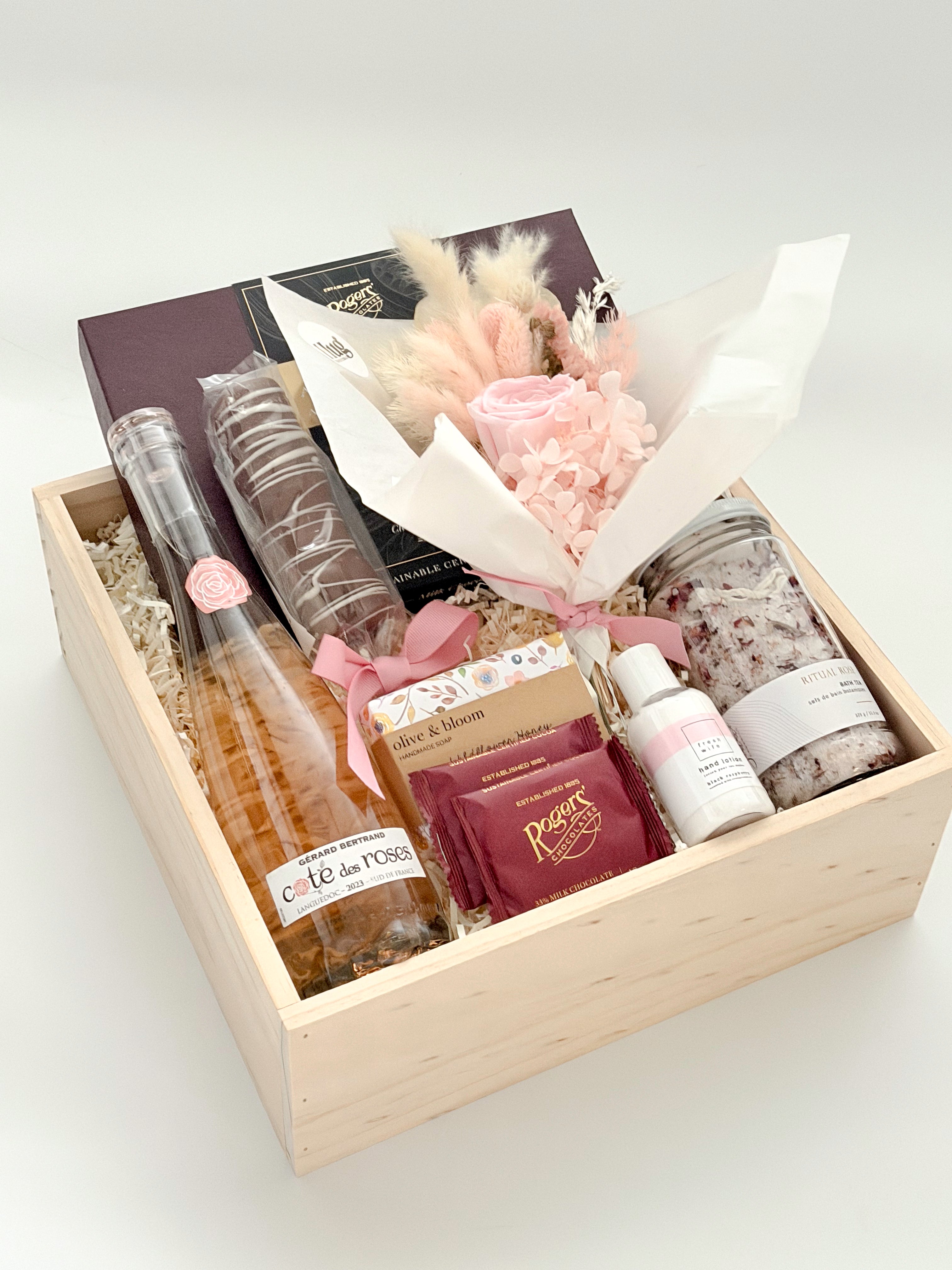 Gift basket with bottles, flowers, and other items on a white background