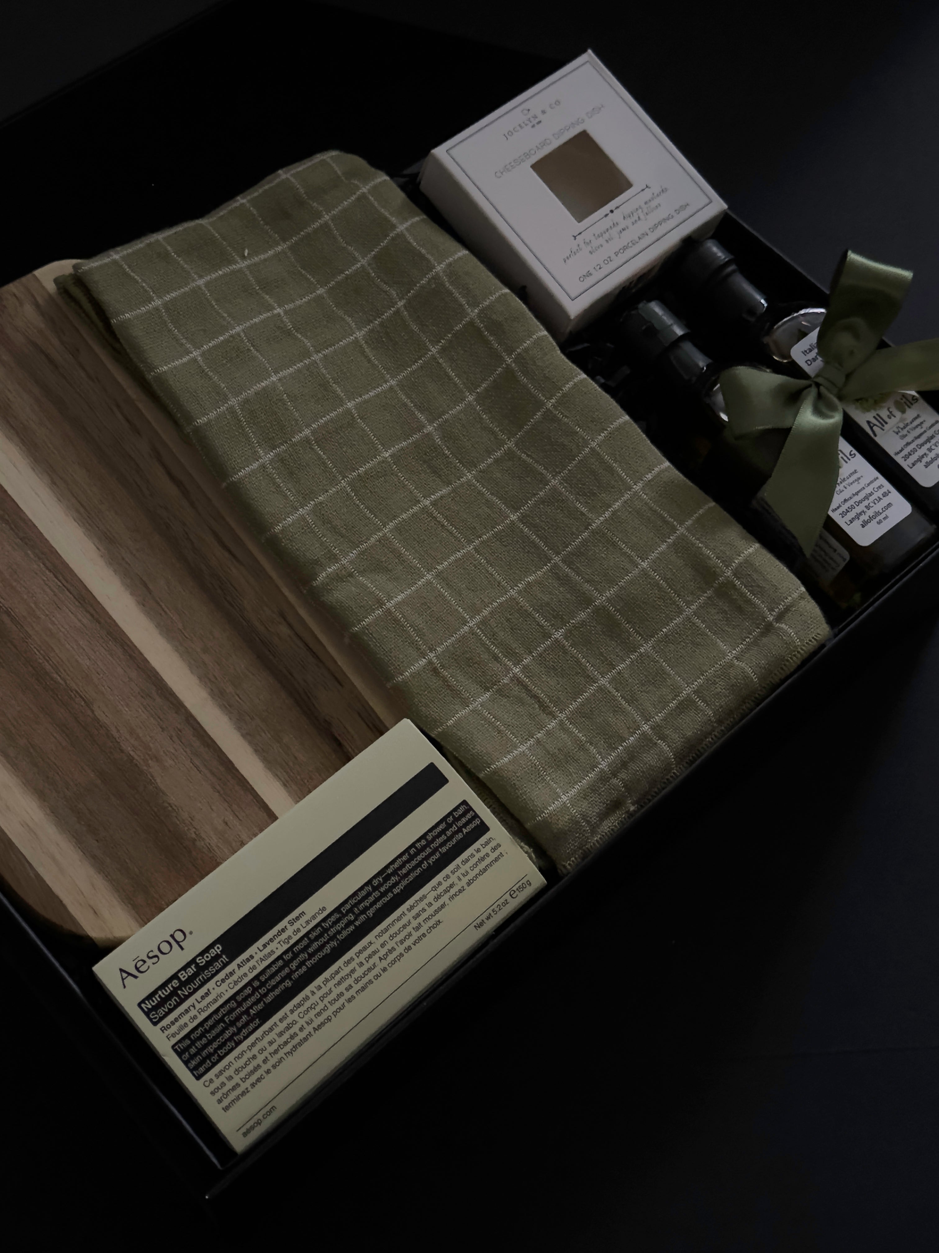 Hestia possession day gift box in black packaging with home and kitchen pieces, including Aēsop soap, acacia wood board, olive oil and balsamic vinegar.