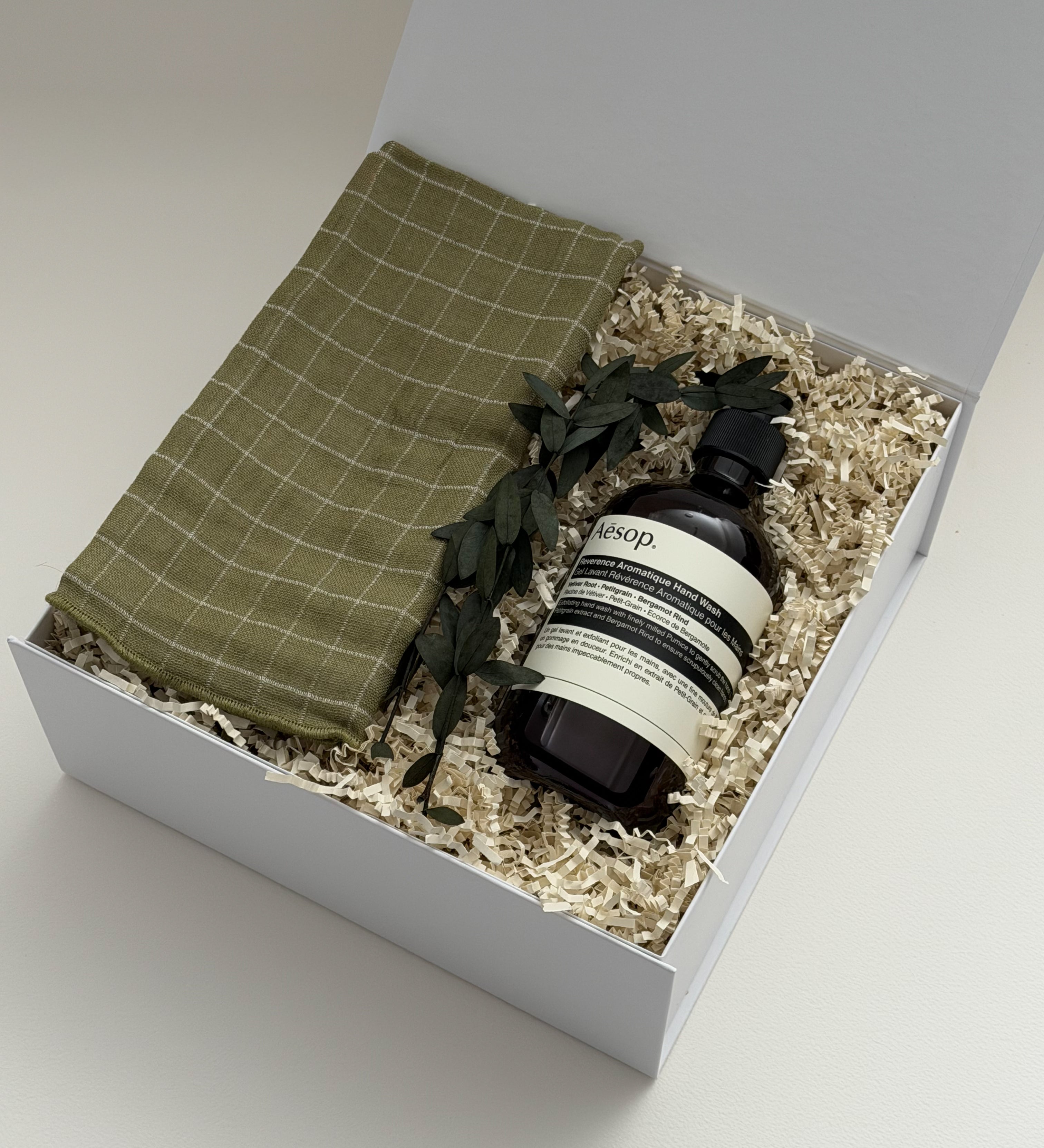 Gift set with a green hand towel and Aesop soap bottle in a white box.